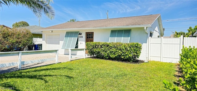 view of front facade with stucco siding, an attached garage, a front yard, and fence