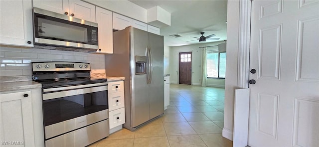 kitchen with decorative backsplash, light countertops, light tile patterned flooring, and appliances with stainless steel finishes