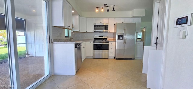 kitchen featuring decorative backsplash, white cabinets, light tile patterned flooring, and stainless steel appliances