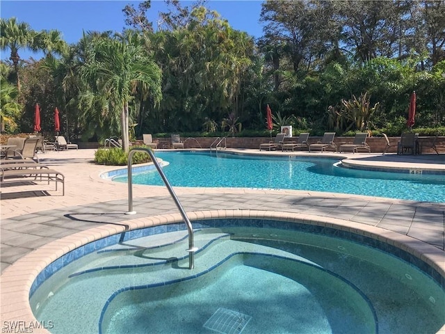 pool featuring a community hot tub and a patio area