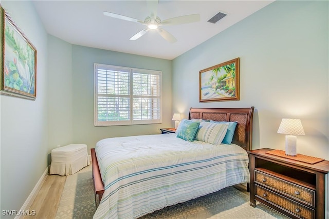 bedroom featuring a ceiling fan, visible vents, baseboards, and wood finished floors