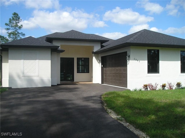 prairie-style home featuring a garage, roof with shingles, driveway, and stucco siding