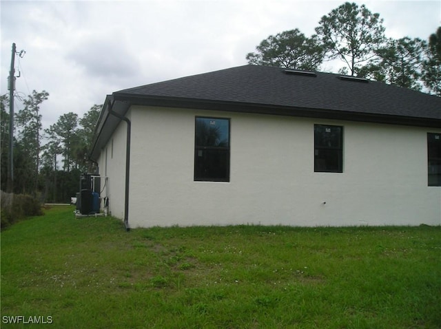 view of home's exterior featuring roof with shingles and a yard