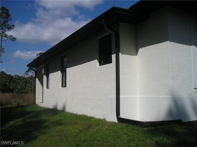 view of side of home featuring a yard and stucco siding