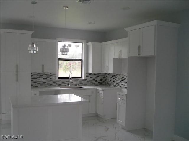 kitchen featuring a center island, marble finish floor, tasteful backsplash, white cabinets, and a sink