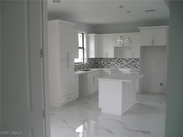 kitchen featuring marble finish floor, backsplash, and white cabinets