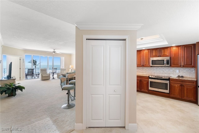 kitchen featuring open floor plan, stainless steel appliances, ornamental molding, and backsplash