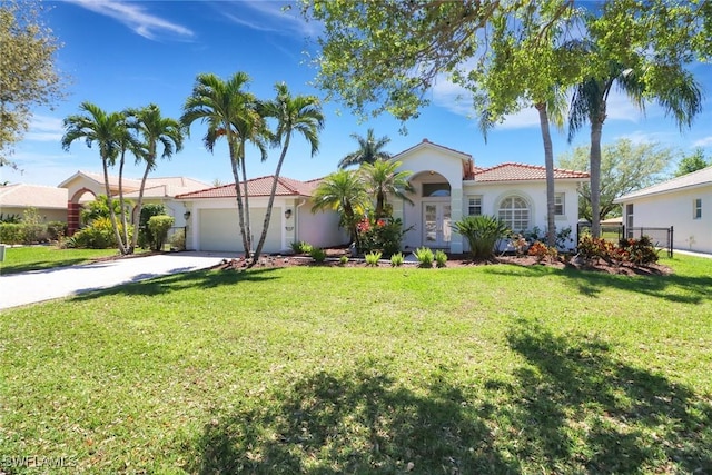 mediterranean / spanish-style home featuring a garage, driveway, a tile roof, a front lawn, and stucco siding