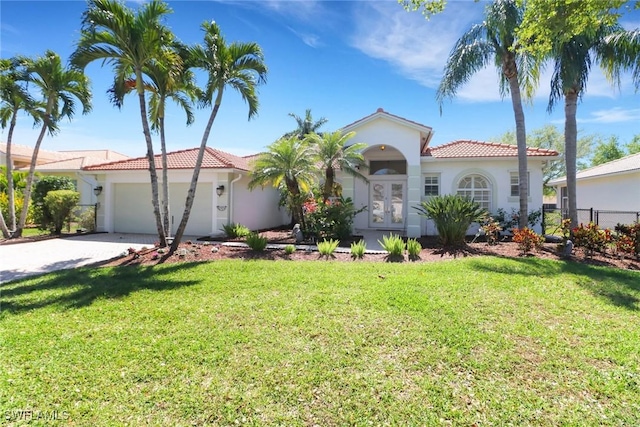 mediterranean / spanish-style home featuring a garage, a tile roof, a front yard, and french doors