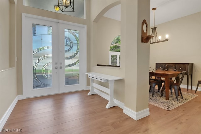 doorway to outside featuring baseboards, french doors, wood finished floors, and a notable chandelier