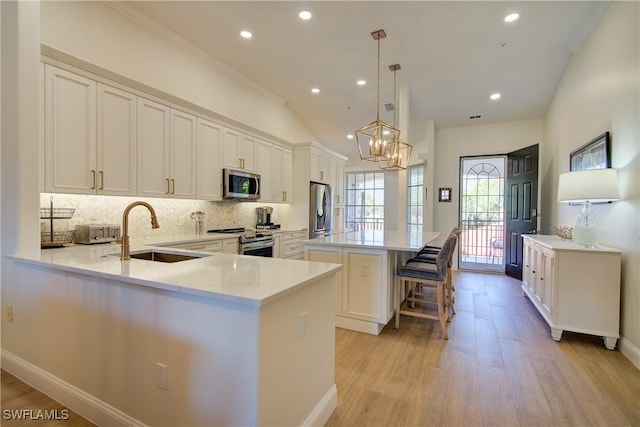 kitchen featuring stainless steel appliances, a kitchen island, a sink, backsplash, and light wood finished floors