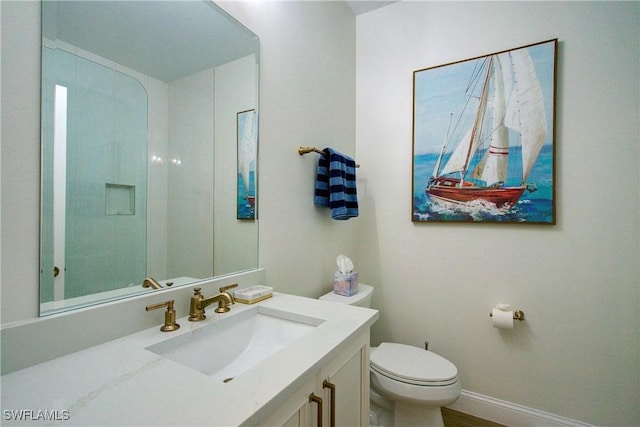 bathroom featuring toilet, baseboards, and vanity