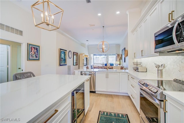 kitchen with appliances with stainless steel finishes, white cabinets, visible vents, and an inviting chandelier