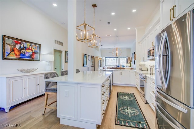 kitchen with visible vents, stainless steel appliances, light countertops, a kitchen bar, and white cabinetry