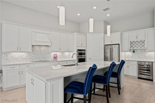 kitchen featuring beverage cooler, a sink, stainless steel appliances, custom range hood, and white cabinets