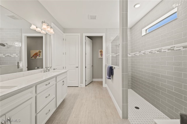 full bath featuring visible vents, baseboards, walk in shower, double vanity, and a sink