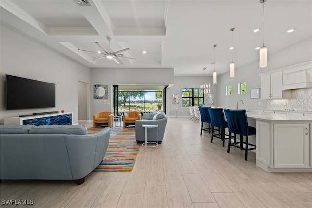 living area with crown molding, ceiling fan, beamed ceiling, a towering ceiling, and coffered ceiling