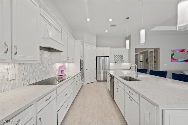 kitchen featuring a sink, stainless steel appliances, a large island, white cabinets, and backsplash