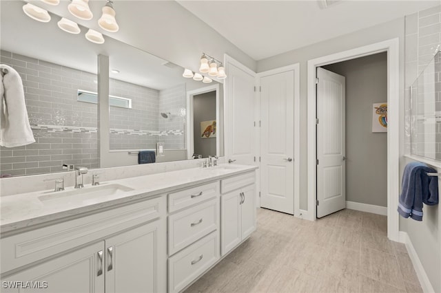 bathroom featuring a sink, baseboards, double vanity, and a walk in shower