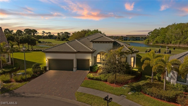 view of front of home with stucco siding, a front lawn, decorative driveway, a garage, and a tiled roof