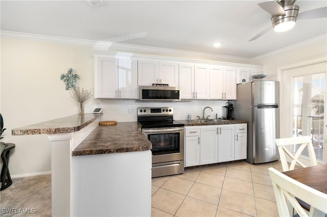 kitchen featuring stainless steel appliances, white cabinetry, a sink, and ornamental molding