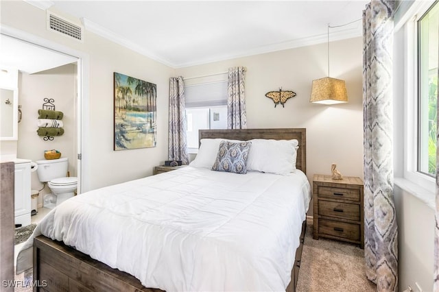 carpeted bedroom featuring ornamental molding, ensuite bath, and visible vents