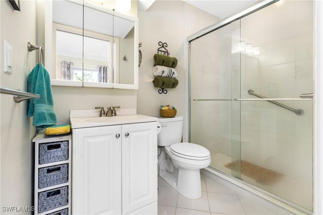 full bathroom with a stall shower, vanity, toilet, and tile patterned floors