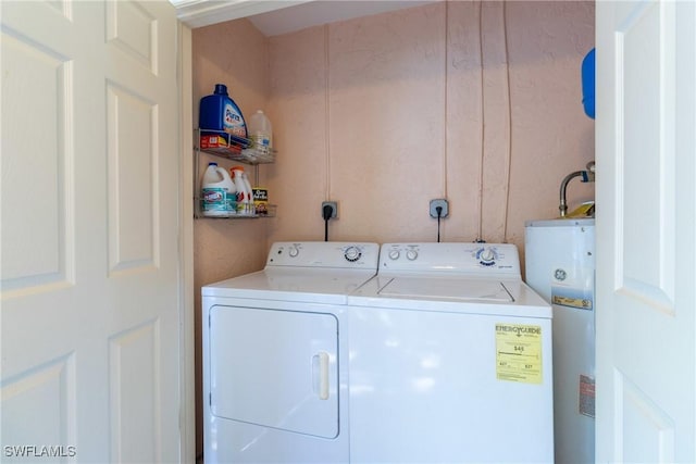 laundry room with water heater, independent washer and dryer, and laundry area
