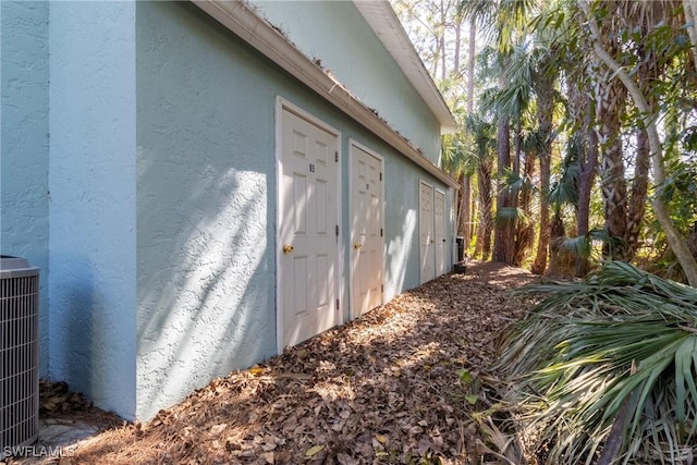 view of side of home with central AC and stucco siding