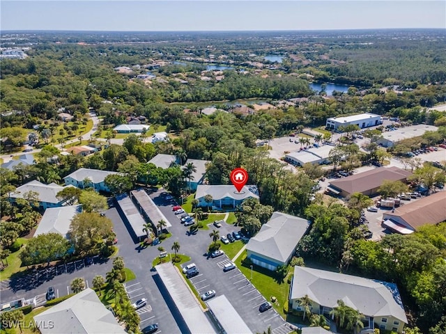 drone / aerial view with a wooded view, a water view, and a residential view