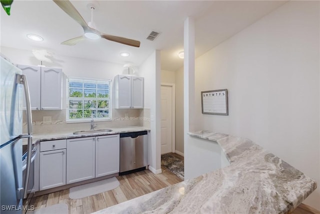 kitchen with tasteful backsplash, a sink, light wood finished floors, visible vents, and appliances with stainless steel finishes