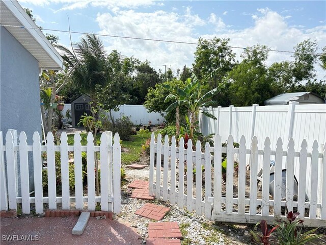 view of yard with a storage shed, a fenced backyard, and an outbuilding