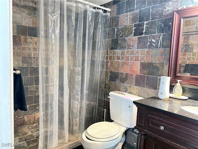 full bathroom with toilet, a tile shower, tile walls, and vanity