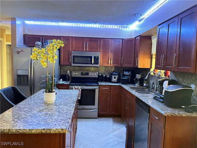 kitchen featuring a sink, light stone countertops, stainless steel appliances, dark brown cabinets, and backsplash