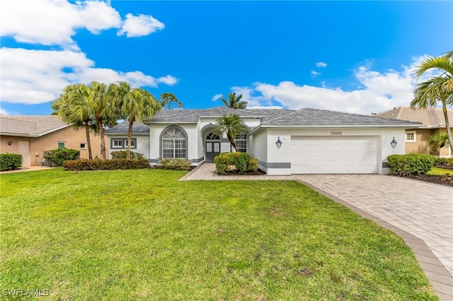 single story home with stucco siding, a garage, decorative driveway, and a front lawn
