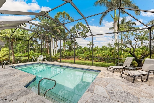 outdoor pool featuring a patio area, a lanai, and view of wooded area