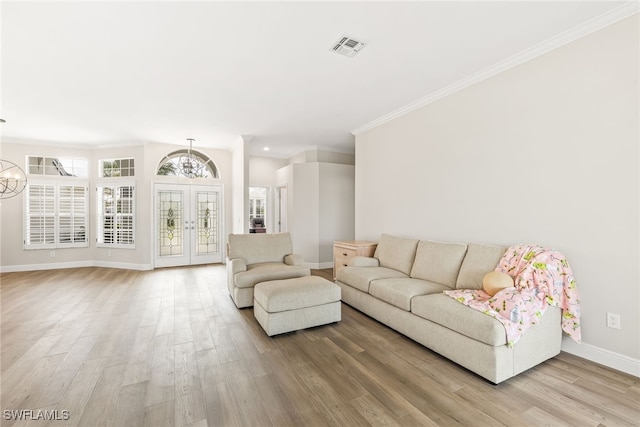 living room featuring baseboards, light wood finished floors, crown molding, french doors, and a chandelier