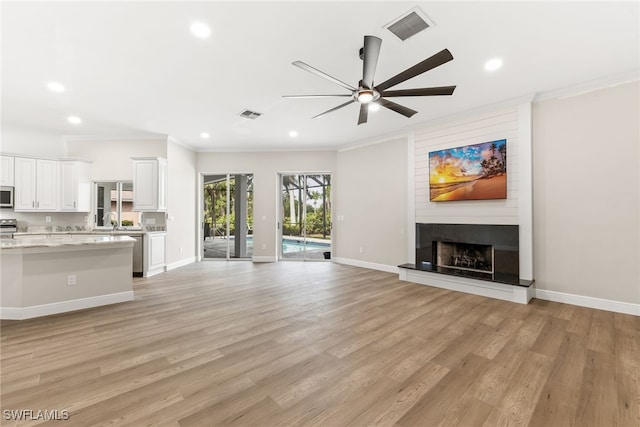 unfurnished living room with crown molding, a ceiling fan, light wood finished floors, recessed lighting, and a fireplace