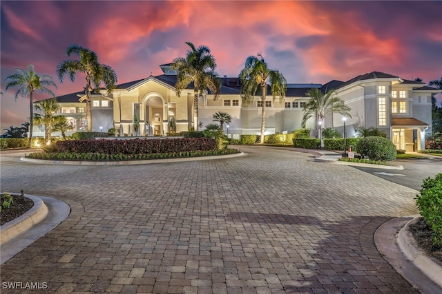 view of front facade featuring stucco siding and curved driveway