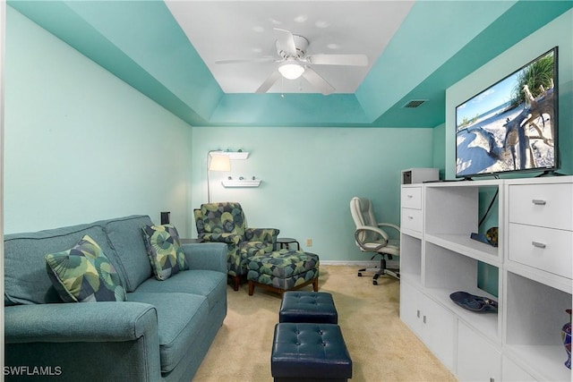 office space with visible vents, a ceiling fan, baseboards, a raised ceiling, and light colored carpet