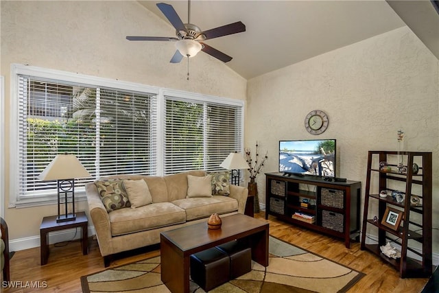 living room featuring wood finished floors, baseboards, ceiling fan, vaulted ceiling, and a textured wall