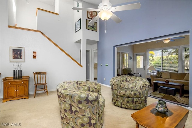 living room with light carpet, ceiling fan, baseboards, and a towering ceiling