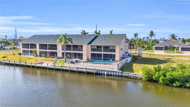 rear view of property with a yard, a patio, a water view, and an outdoor pool