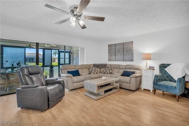 living area featuring a ceiling fan, light wood-style flooring, and a textured ceiling