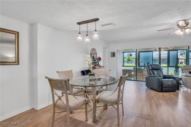 dining area with baseboards, a textured ceiling, visible vents, and wood finished floors