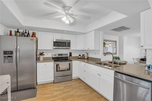 kitchen featuring visible vents, light wood-style flooring, light stone countertops, stainless steel appliances, and a sink