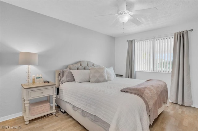 bedroom with ceiling fan, wood finished floors, and baseboards