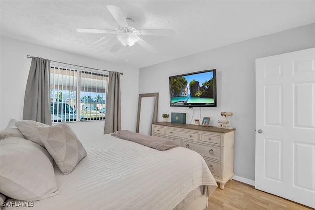 bedroom featuring baseboards, a textured ceiling, a ceiling fan, and light wood-style floors