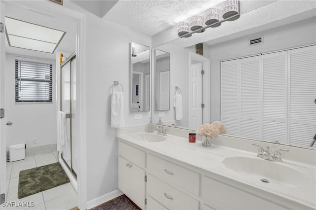 full bathroom with double vanity, visible vents, a sink, a shower stall, and a textured ceiling