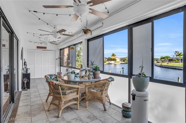 sunroom featuring a water view and a ceiling fan